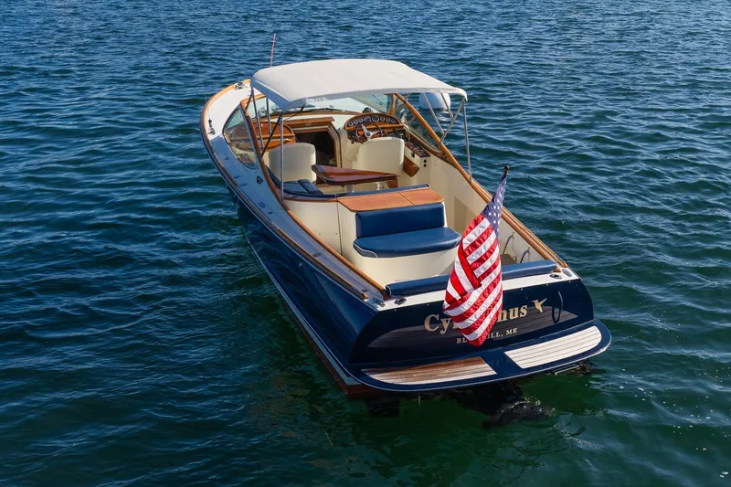 Slide: The Image of 2008 Hinckley Talaria 29R boat on water with American flag, rear view. - 2