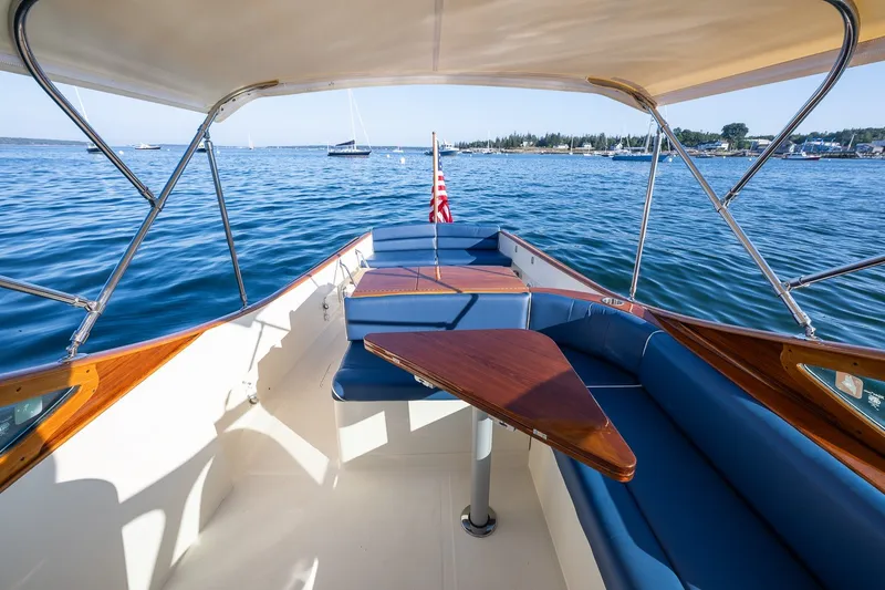 Slide: The Image of Hinckley Talaria 29R 2008 boat interior with blue seating and wooden table on calm water. - 27