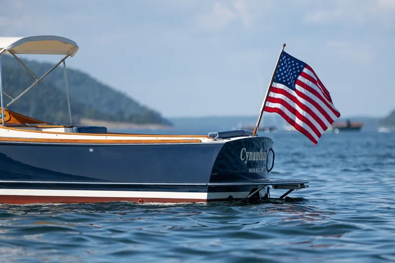 Slide: The Image of 2008 Hinckley Talaria 29R boat with American flag on calm water. - 8