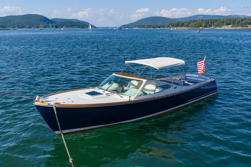 Slide: The Image of 2008 Hinckley Talaria 29R boat on calm water with scenic mountain backdrop. - 1