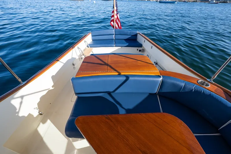 Slide: The Image of Hinckley Talaria 29R 2008 boat interior with blue seating and wooden table on calm water. - 28