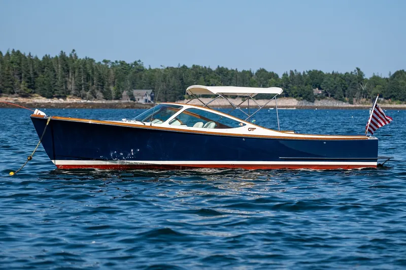 Slide: The Image of 2008 Hinckley Talaria 29R boat on calm water with forested shoreline background. - 34