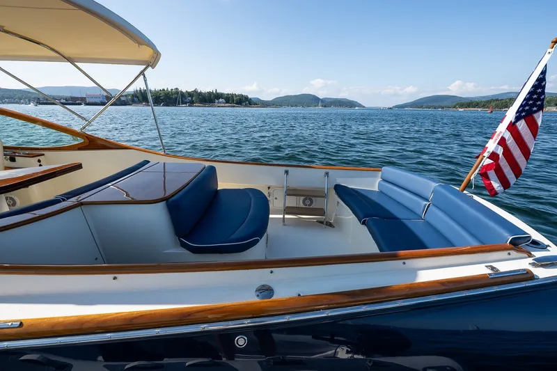 Slide: The Image of 2008 Hinckley Talaria 29R boat with blue seating, American flag, scenic water view. - 25
