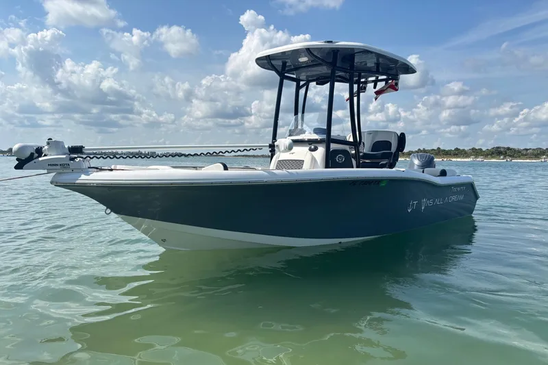 Slide: The Image of 2025 Tidewater 210 LXF boat on calm water under a partly cloudy sky. - 2