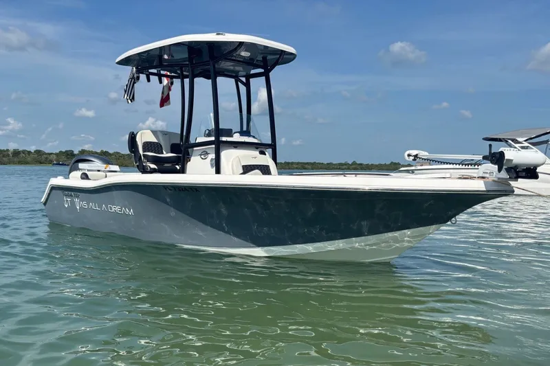 Slide: The Image of 2025 Tidewater 210 LXF boat on calm water under clear blue sky. - 0