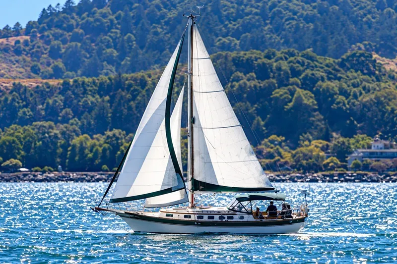 The Image of Sailboat Gozzard Cutter 36 (1988) cruising on a sunny day with lush hills in background. - 0
