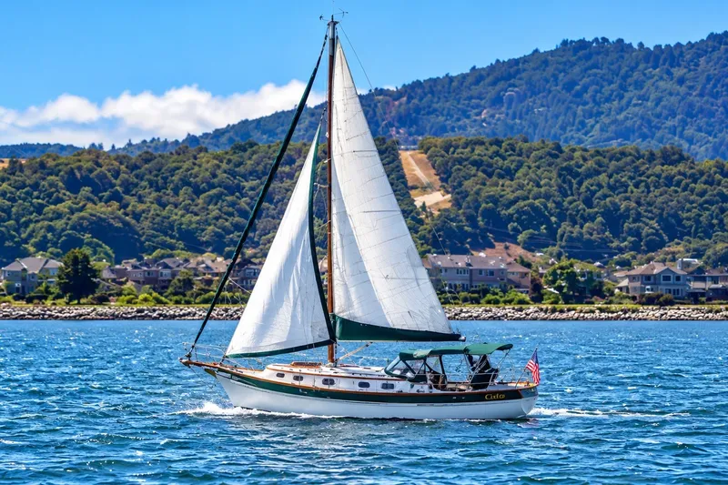 Slide: The Image of Sailboat Gozzard Cutter 36 (1988) cruising on a scenic lake with hills in the background. - 1