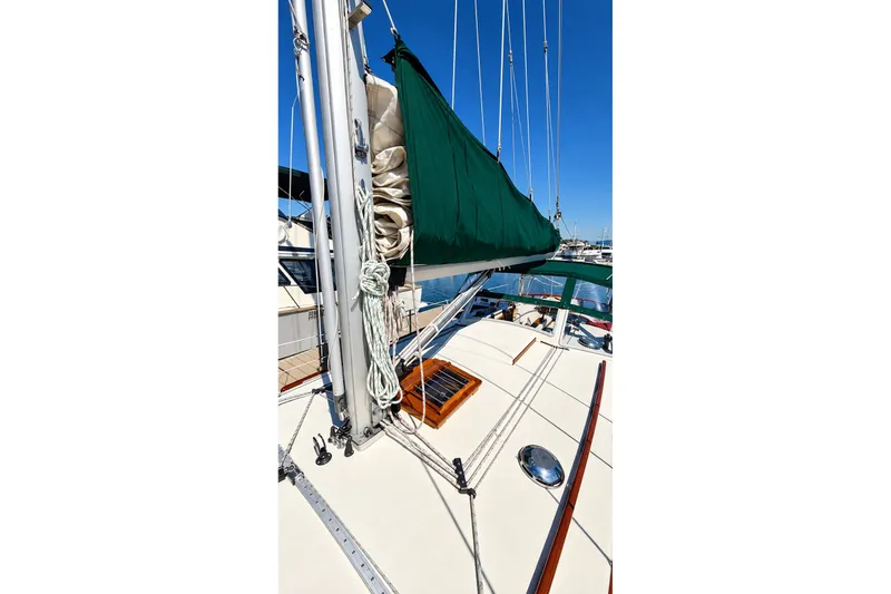 Slide: The Image of 1988 Gozzard Cutter 36 sailboat deck with green sail cover, docked in marina. - 12
