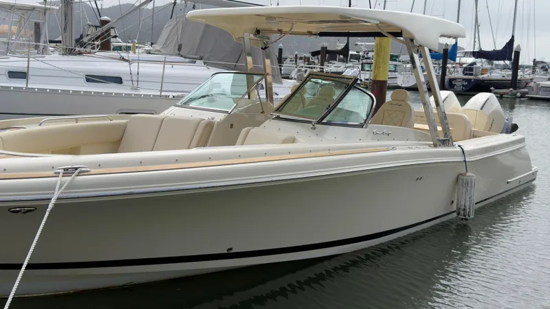 The Image of A sleek, cream-colored boat with an open deck and protective hardtop, docked in a marina. - 0