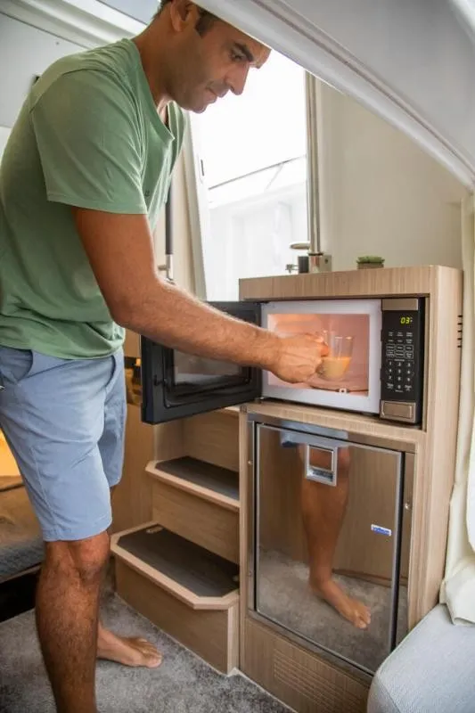 Slide: The Image of A man uses a microwave in the cabin of a Jeanneau Leader 10.5 CC boat. - 24