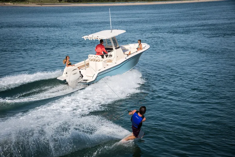 Slide: The Image of A Grady-White Fisherman 216 boat pulls a water skier across calm waters. Three people are on board. - 11