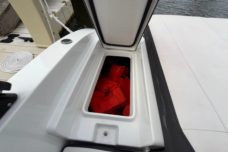 Slide: The Image of Open storage compartment on 2019 Monterey M-22 boat with red life jackets inside. - 36