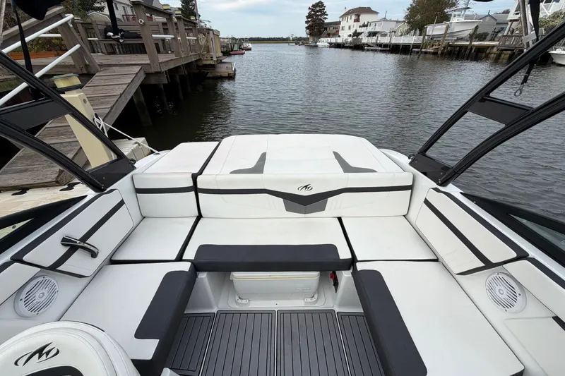Slide: The Image of 2019 Monterey M-22 boat interior with sleek white seating, docked by a serene waterfront. - 19