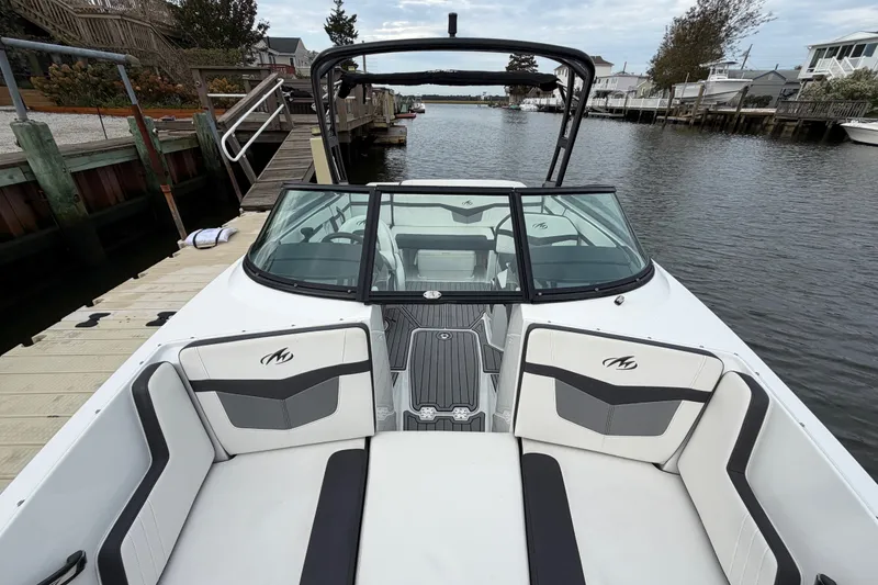 Slide: The Image of 2019 Monterey M-22 boat docked by a wooden pier, featuring sleek seating and windshield. - 28