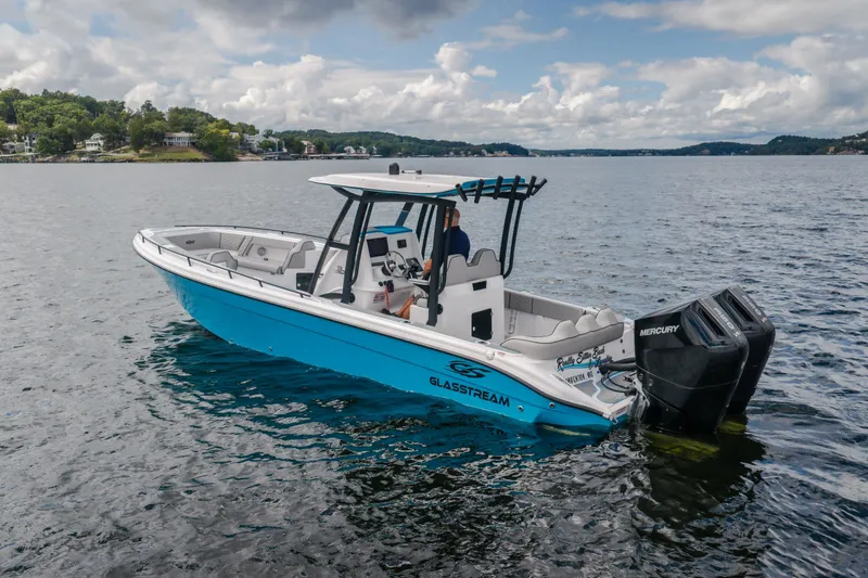 Slide: The Image of 2024 Glasstream 32 GSX boat on a scenic lake with dual Mercury engines. - 6