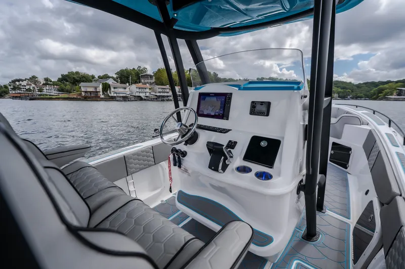 Slide: The Image of 2024 Glasstream 32 GSX boat interior with modern dashboard and steering, on a scenic lake. - 15