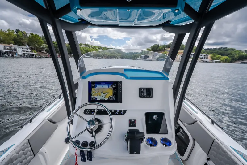 Slide: The Image of 2024 Glasstream 32 GSX boat cockpit with steering wheel and navigation display on a lake. - 16