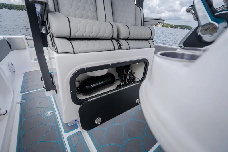 Slide: The Image of 2024 Glasstream 32 GSX boat interior with open storage compartment, gray seating, and blue-accented flooring. - 22