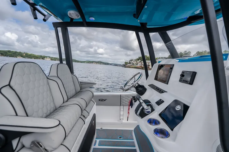 Slide: The Image of 2024 Glasstream 32 GSX boat interior with modern dashboard and seating on a scenic lake. - 21