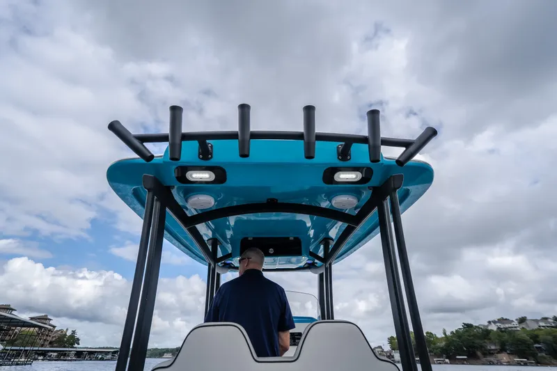 Slide: The Image of 2024 Glasstream 32 GSX boat with blue canopy, viewed from behind, under cloudy sky. - 32