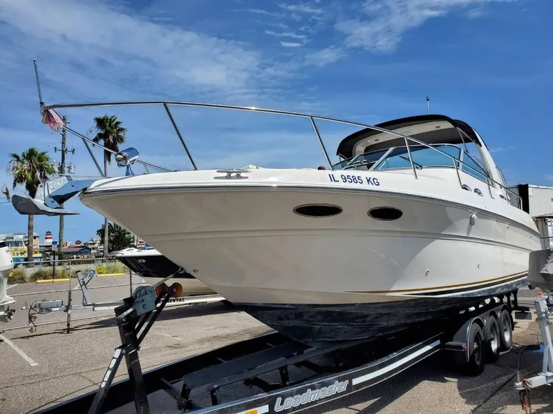 Slide: The Image of 2002 Sea Ray 310 Sundancer boat on trailer, parked outdoors under clear blue sky. - 4