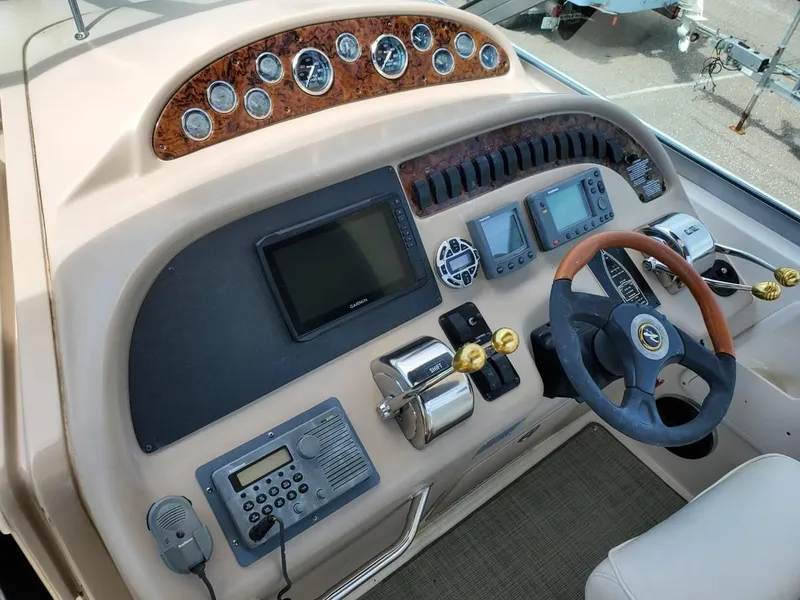 Slide: The Image of 2002 Sea Ray 310 Sundancer helm with gauges, steering wheel, and navigation equipment. - 29