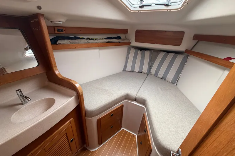 Slide: The Image of Cozy cabin interior of 1998 Catalina 380 sailboat with bed, sink, and striped pillows. - 14