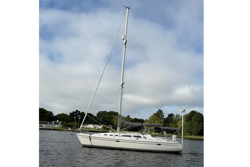 Slide: The Image of 1998 Catalina 380 sailboat anchored on a calm lake under a cloudy sky. - 36