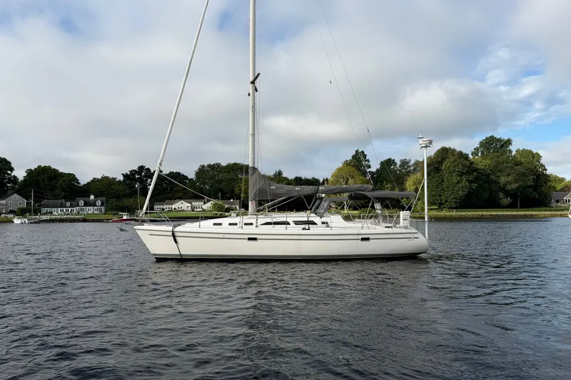 The Image of 1998 Catalina 380 sailboat anchored on a calm lake with scenic shoreline backdrop. - 0
