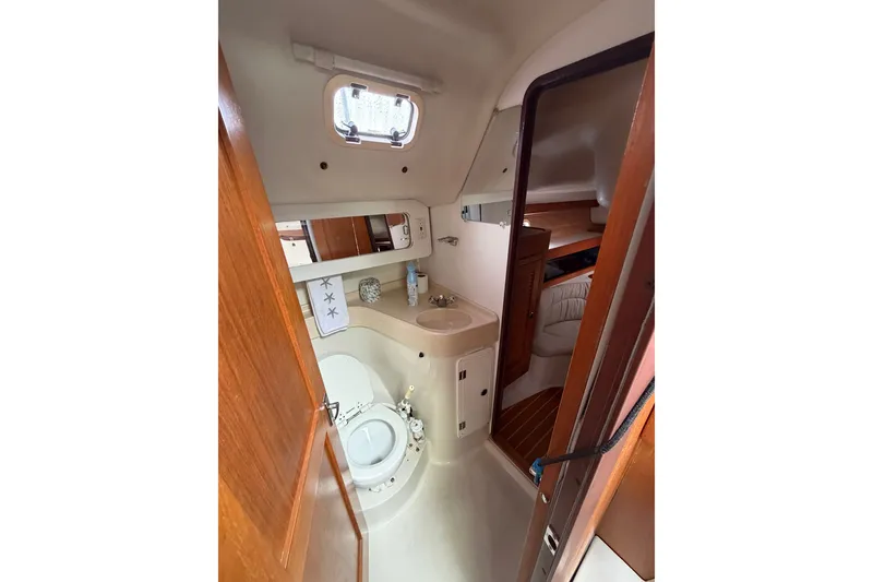 Slide: The Image of Bathroom interior of a 1998 Catalina 380 sailboat, featuring a compact design with wooden accents. - 12