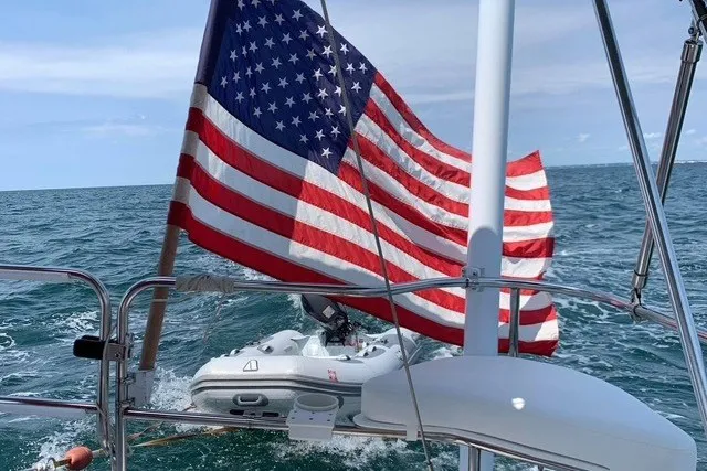 Slide: The Image of Sailing on a 1998 Catalina 380 with American flag and inflatable boat in tow. - 39