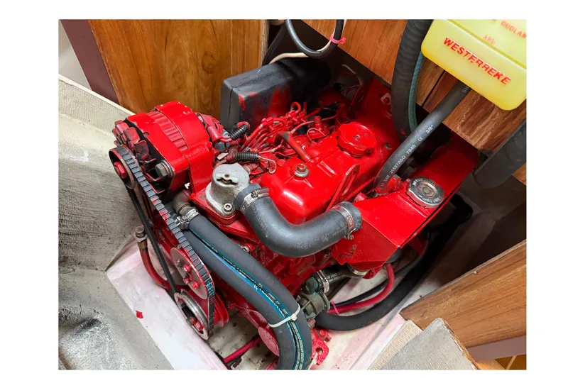 Slide: The Image of Red engine of a 1998 Catalina 380 sailboat, featuring hoses and belts. - 37