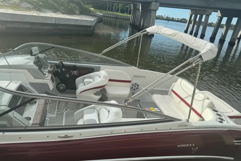 Slide: The Image of 2011 Formula 270 Bowrider boat with white and red interior, docked near a bridge. - 25