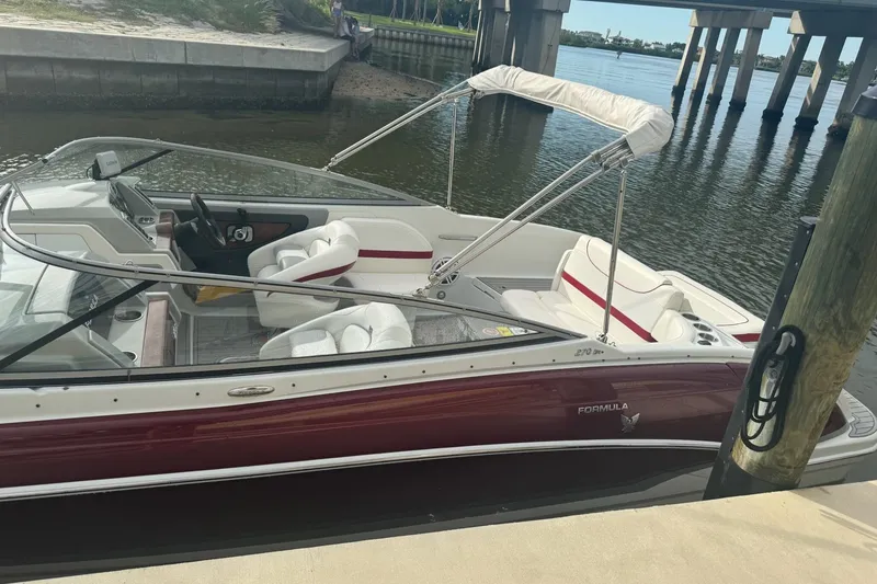 Slide: The Image of 2011 Formula 270 Bowrider boat docked by a bridge, featuring white and red seating. - 26