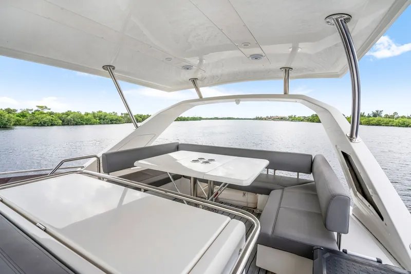 Slide: The Image of 2019 Aquila 44 Yacht interior with seating area and table, overlooking serene water and greenery. - 33