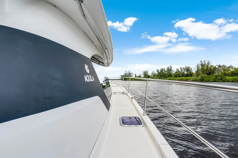 Slide: The Image of 2019 Aquila 44 Yacht cruising on a serene river under a clear blue sky. - 20