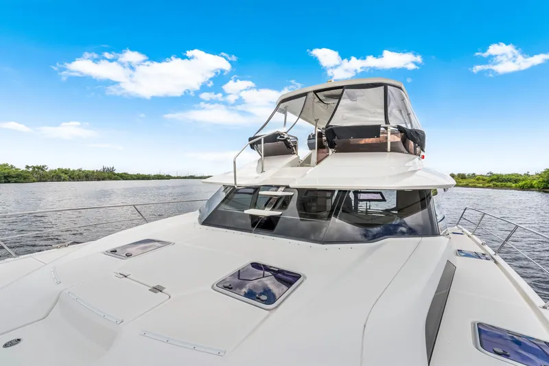 Slide: The Image of 2019 Aquila 44 Yacht cruising on a serene river under a clear blue sky. - 17