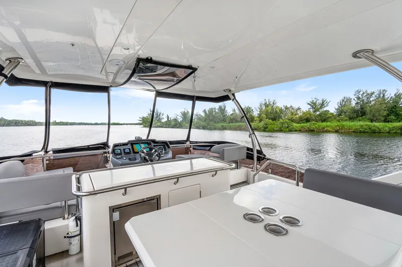 Slide: The Image of Interior view of 2019 Aquila 44 Yacht helm and seating area on a serene waterway. - 31