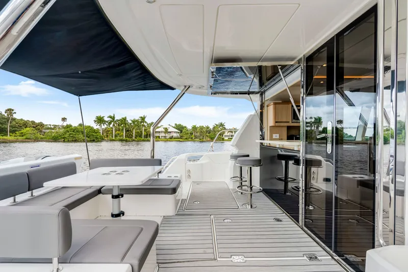 Slide: The Image of Luxurious 2019 Aquila 44 Yacht deck with seating, bar stools, and scenic water view. - 23