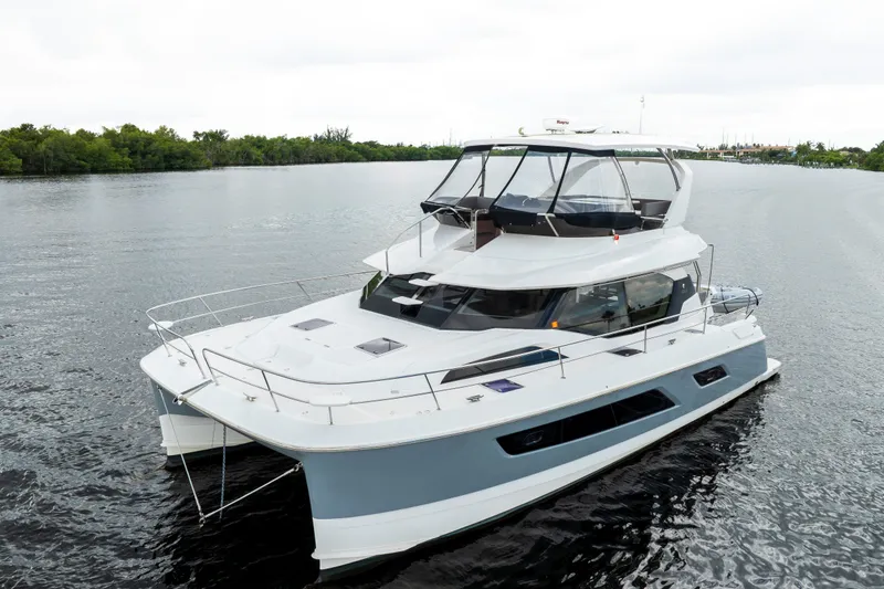The Image of 2019 Aquila 44 Yacht cruising on a calm river with lush greenery. - 1