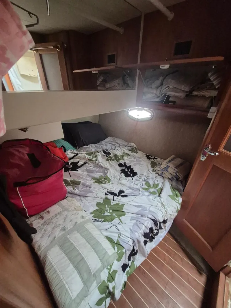 Slide: The Image of Cozy cabin interior of 2002 Silverton 38 Convertible with bed and storage shelves. - 31