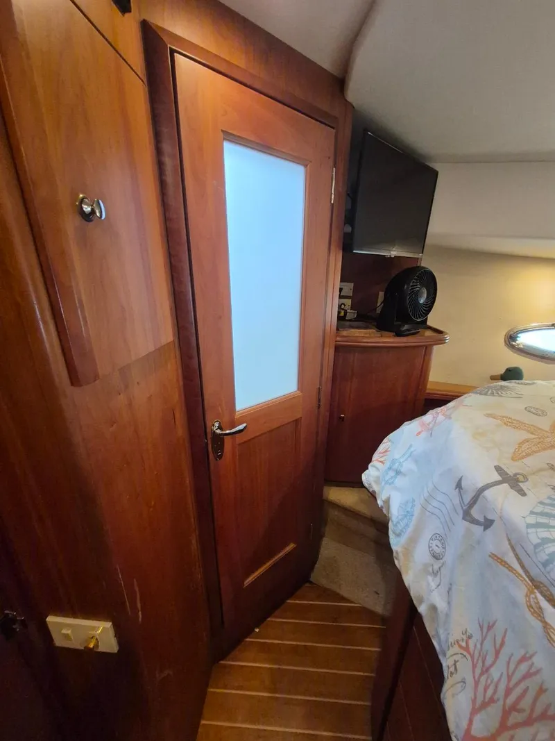 Slide: The Image of Interior of 2002 Silverton 38 Convertible yacht with wooden door and nautical-themed bedding. - 34