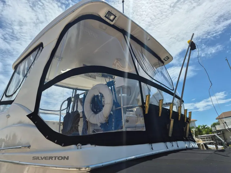 Slide: The Image of 2002 Silverton 38 Convertible boat with clear enclosure and fishing rod holders. - 7