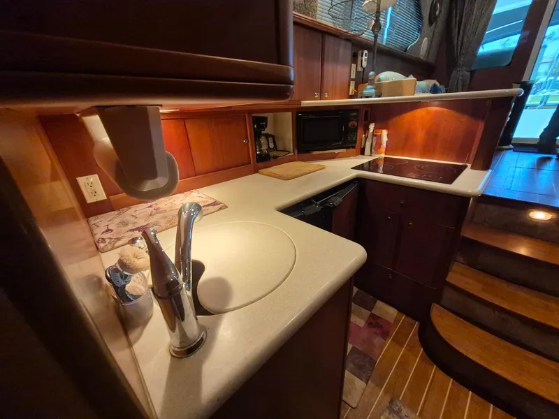 Slide: The Image of 2002 Silverton 38 Convertible yacht kitchen with sink, stove, and wooden cabinetry. - 37