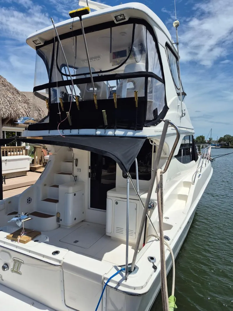 Slide: The Image of 2002 Silverton 38 Convertible yacht docked, featuring spacious deck and flybridge under clear skies. - 3