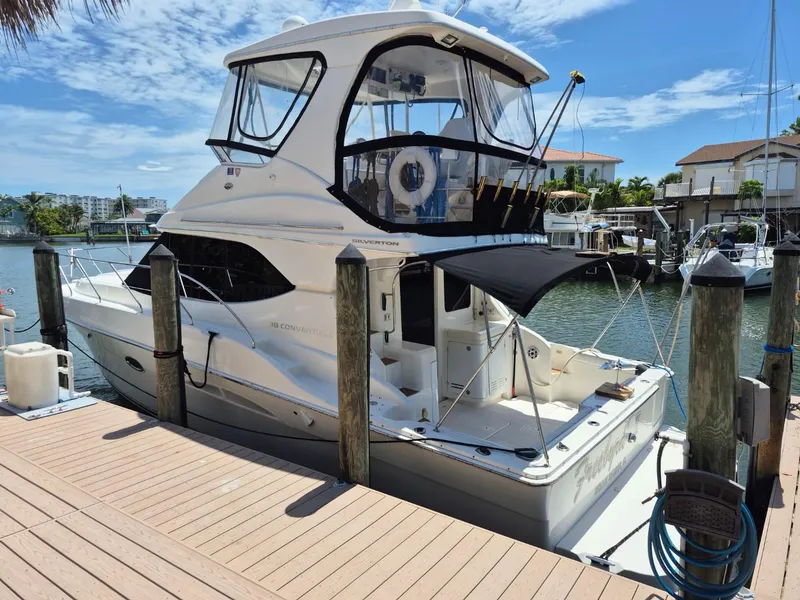 The Image of 2002 Silverton 38 Convertible yacht docked at marina under clear blue sky. - 1