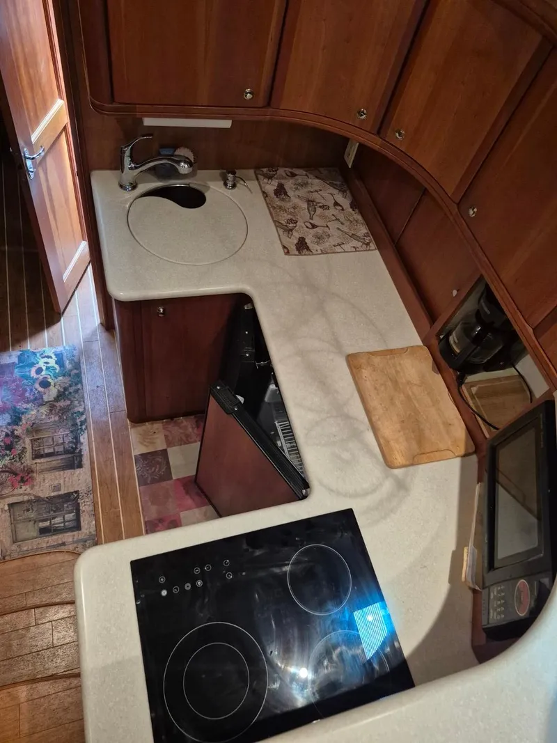 Slide: The Image of 2002 Silverton 38 Convertible yacht kitchen with stove, sink, and wooden cabinetry. - 28