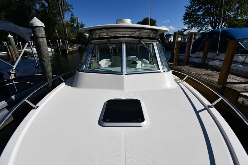 Slide: The Image of 2004 Pursuit 2670 Denali LS boat docked, showcasing sleek design and spacious deck. - 5