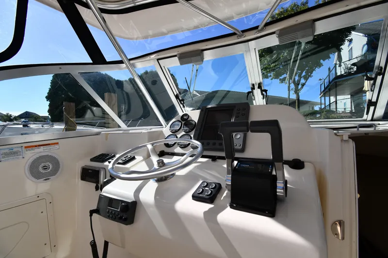 Slide: The Image of 2004 Pursuit 2670 Denali LS boat cockpit with steering wheel and navigation controls. - 9