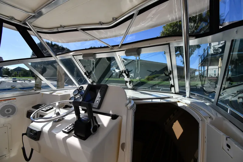 Slide: The Image of 2004 Pursuit 2670 Denali LS boat cockpit with steering wheel and navigation controls. - 8
